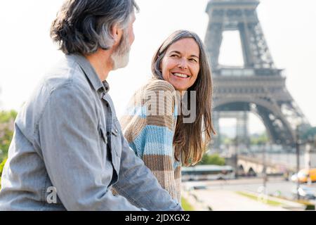 Glückliche, reife Frau, die den Mann vor dem Eiffelturm in Paris, Frankreich, ansieht Stockfoto