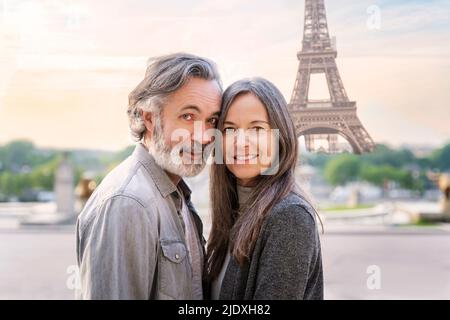 Lächelnde Frau mit Mann, der vor dem Eiffelturm, Paris, Frankreich, steht Stockfoto
