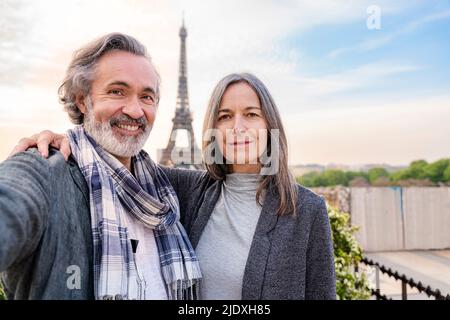 Glücklicher Mann, der ein Selfie mit einer Frau vor dem Eiffelturm, Paris, Frankreich, macht Stockfoto