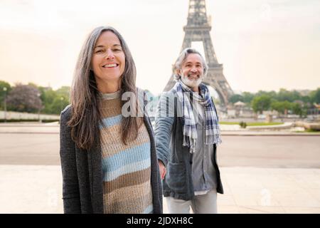 Glückliche reife Frau mit Mann vor dem Eiffelturm, Paris, Frankreich an einem sonnigen Tag Stockfoto