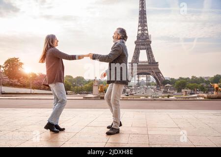 Glücklicher reifer Mann mit Frau, die vor dem Eiffelturm, Paris, Frankreich tanzt Stockfoto