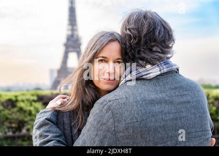 Lächelnde reife Frau umarmt Mann vor dem Eiffelturm, Paris, Frankreich Stockfoto