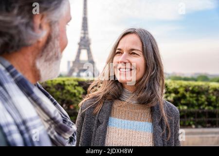 Lächelnde reife Frau, die den Mann vor dem Eiffelturm, Paris, Frankreich, ansieht Stockfoto