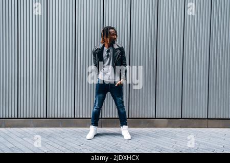 Junger Mann vor einer gestreiften Wand, der auf einem Fußweg steht Stockfoto