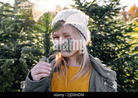 Mädchen hält Tannenzweig winken auf Weihnachtsbaum Bauernhof Stockfoto