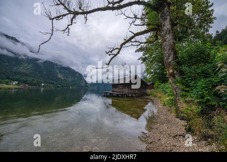 Österreich, Steiermark, Altaussee, niedrige Wolken über dem Ufer des Altaussees mit Bootshaus im Hintergrund Stockfoto