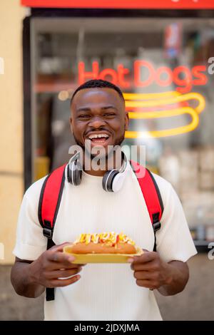 Glücklicher junger Mann mit Hot Dog Stockfoto
