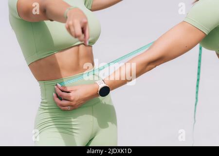 Hand einer Frau, die die Taille der Schwester misst Stockfoto