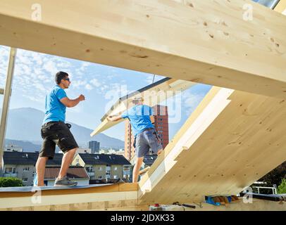 Bauarbeiter arbeiten auf Holzdach des Hauses Stockfoto