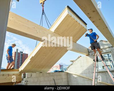 Arbeiter, die auf der Baustelle auf dem Dach des Hauses arbeiten Stockfoto