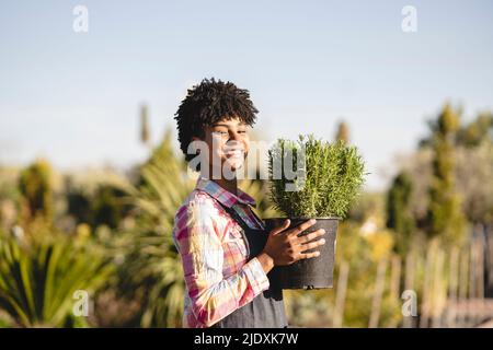 Selbstbewusster Gärtner, der die Topfpflanze in der Gärtnerei hält Stockfoto