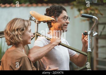 Reife Frau mit Mann, der Fahrrad auf der Schulter trägt Stockfoto