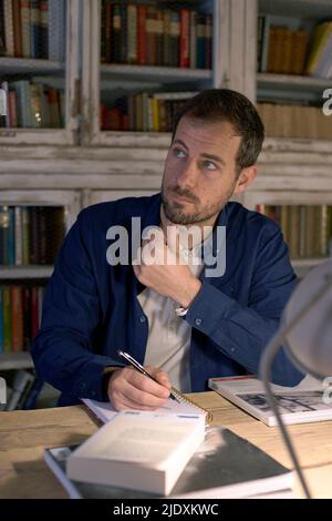 Besinnlicher Geschäftsmann mit Buch am Schreibtisch zu Hause Stockfoto