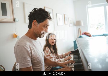 Vater und Tochter spielen zu Hause zusammen Klavier Stockfoto