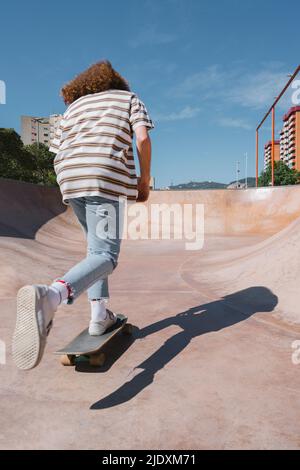 Junger Mann Skateboarding auf Sportrampe an sonnigen Tag Stockfoto