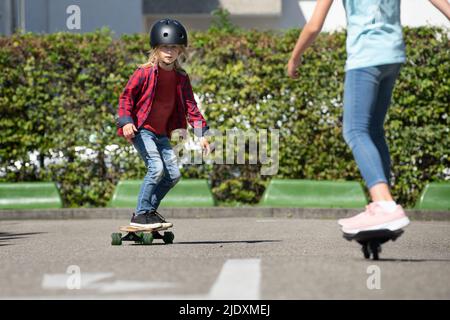 Junge trägt Helm Skateboarding mit Freund auf dem Verkehrskurs Stockfoto