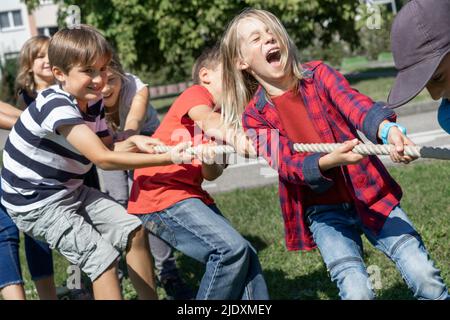 Glückliche Kinder, die an sonnigen Tagen das Tauziehen genießen Stockfoto