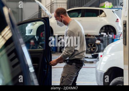 Automechaniker, der in der Werkstatt an der Autotür arbeitet Stockfoto