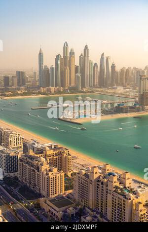 Vereinigte Arabische Emirate, Dubai, Gebäude von Palm Jumeirah mit Yachthafen und Wolkenkratzern in der Innenstadt im Hintergrund Stockfoto