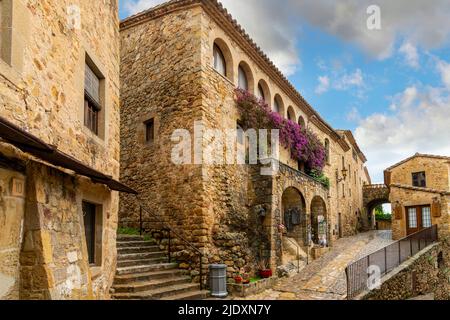Ein kleines Geschäft mit violetten Bougainvillea-Büschen im mittelalterlichen ummauerten Dorf Pals Spanien an der Costa Brava. Stockfoto