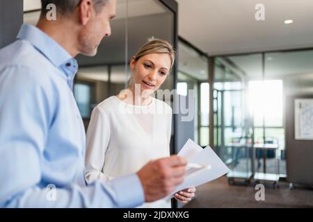 Geschäftsmann und Geschäftsfrau mit digitalem Tablet und Dokumenten im Büro Stockfoto