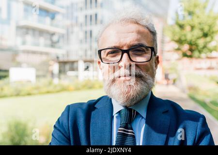 Leitender Geschäftsmann mit Brillen, der im Büropark steht Stockfoto