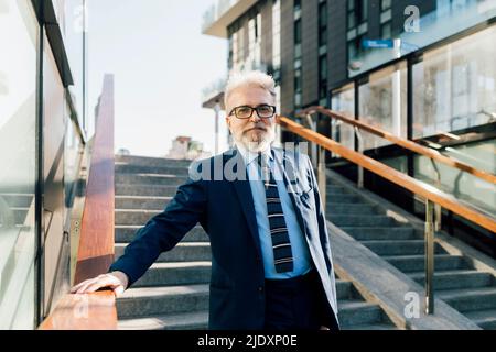 Ein älterer Geschäftsmann, der im Freien über die Treppe hinuntergeht Stockfoto