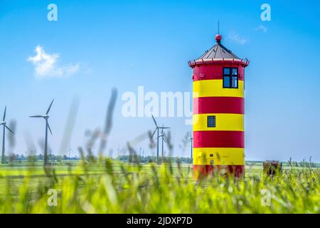 Deutschland, Niedersachsen, Krummhorn, Pilsum Leuchtturm im Frühjahr mit Windpark im Hintergrund Stockfoto