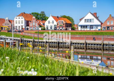 Deutschland, Niedersachsen, Greetsiel, Stadthafen im Frühjahr mit Häusern im Hintergrund Stockfoto