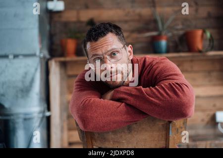 Reifer Mann mit Brille auf Stuhl sitzend Stockfoto