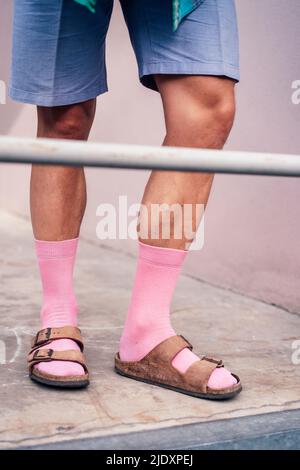 Beine eines Mannes in rosa Socken und Sandalen Stockfoto