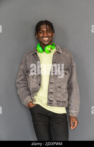 Lächelnder Mann mit Kopfhörern um den Hals vor der Wand Stockfoto