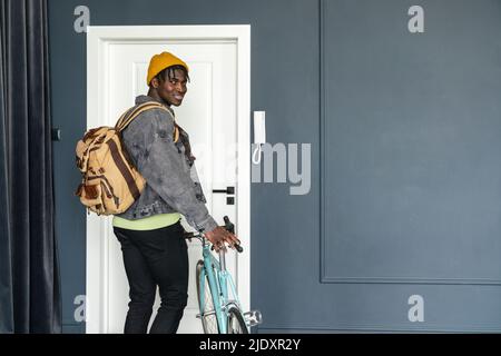 Lächelnder Student mit Fahrrad vor der Tür Stockfoto