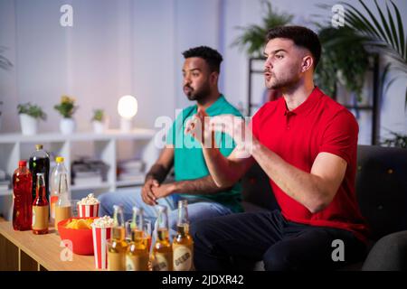 Neugierige Fans sehen sich das Fußballspiel zu Hause gemeinsam an Stockfoto