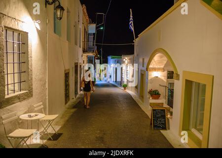 Architektonische Gebäude mit Menschen, die in den Straßen des Dorfes Chora in der Nacht zu Fuß. Stadtfotografie des malerischen Dorfes Chora in Kythera ist Stockfoto