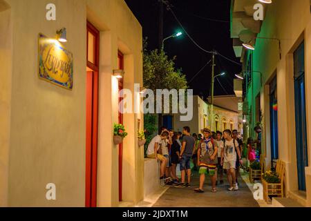 Architektonische Gebäude mit Menschen, die in den Straßen des Dorfes Chora in der Nacht zu Fuß. Stadtfotografie des malerischen Dorfes Chora in Kythera ist Stockfoto