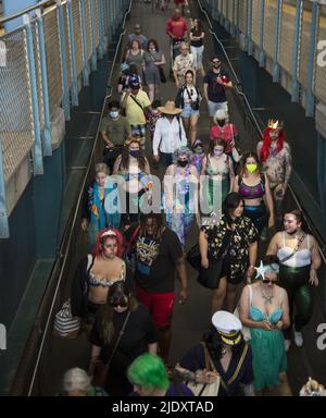 Nach 2 Jahren nach der Schließung von Covid-19 kehren die Menschen zur jährlichen Mermaid Parade zurück, die angeblich die größte Kunstparade des Landes ist, und zwar auf Coney Island entlang der Surf Avenue in Brooklyn, New York. Die Besucher der Parade sehen sich die U-Bahn-Station an der Stillwell Avenue an. Stockfoto