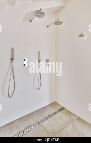 Glänzende Duschhähne, die an einer gefliesten Wand in einem Badezimmer zu Hause angebracht sind Stockfoto