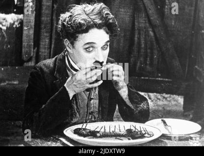 Charlie Chaplin als der Tramp greift in dem Film The Gold Rush von 1925 auf seinen Stiefel zurück. Stockfoto