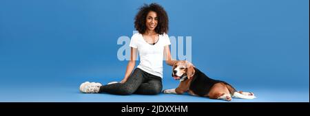 Banner mit schönen afroamerikanischen Frau und niedlichen Hund auf hellblauem Hintergrund Stockfoto