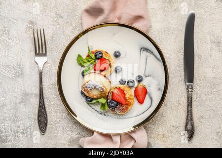 Teller mit leckeren Hüttenkäse-Pfannkuchen und Beeren auf grunge Hintergrund serviert Stockfoto