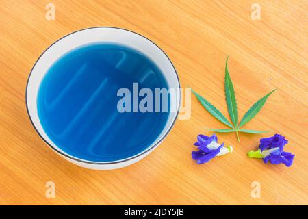 Cannabis, Marihuana und Blue Pea, heißer Kräutertee auf der Schüssel mit Cannabisblatt und Blue Pea Blume. Stockfoto