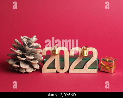 Weihnachtsdekoration mit der Jahreszahl 2022 in Holzbuchstaben auf rotem Hintergrund mit Platz für Text Stockfoto
