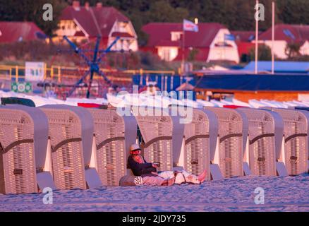 Rostock, Deutschland. 24.. Juni 2022. Urlauber beobachten am frühen Morgen die aufgehende Sonne am Strand in Warnemünde. Meteorologen erwarten in den kommenden Tagen schönes Sommerwetter mit Temperaturen bis zu 30 Grad. Quelle: Jens Büttner/dpa/Alamy Live News Stockfoto