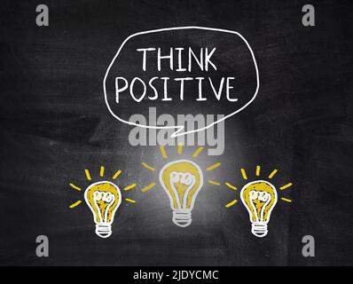 Denken Sie positiven Text und Glühbirnen auf der Tafel. Konzept mit positiver Denkweise und Inspiration Motivation zu erhalten Stockfoto