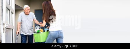 Älterer Mann mit Stock mit Hilfe seiner jungen Tochter Lebensmittel tragen Stockfoto