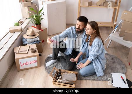 Neues Home Move-Konzept, junges Paar, das Selfie in einer neuen Wohnung macht, Familienumzug ins Light House, Lebensmomente Mann und Frau mit Smartphone, Memo Stockfoto