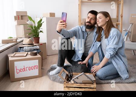 Nahaufnahme Porträt von aufgeregt jubeln fröhlich attraktiv sorglos schöne niedliche Paar fotografieren in der neuen Wohnung. Foto auf dem Smartphone. Photogr Stockfoto