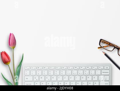 Draufsicht mit Tastatur, Brille, rosa Tulpe und Bleistift auf weißem Tischhintergrund am Büroarbeitsplatz. Stockfoto