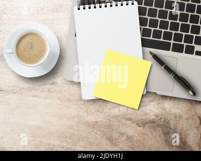 Leeres gelbes Haftpapier, Notebook auf Laptop-Tastatur, Stift und Kaffeetasse auf Büroschreibtischhintergrund. Draufsicht mit Kopierbereich. Stockfoto